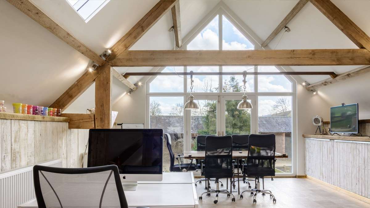 The first floor of the ergo creative office, a sunny day, 2 empty desks, one woth 2 chairs and one with 5