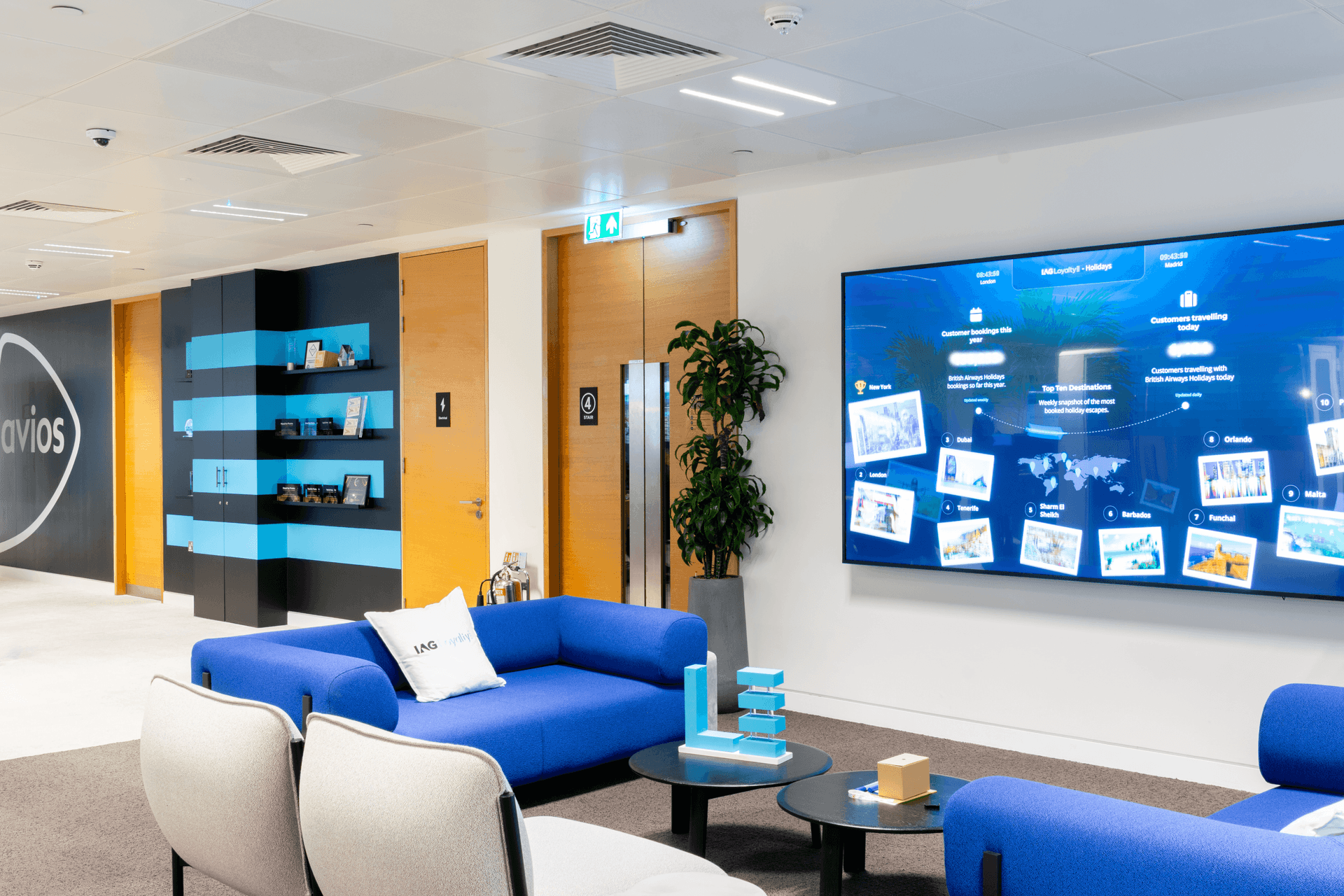 A workspace with sofas, chairs and a large screen TV on the wall